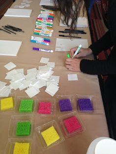 a woman sitting at a table with many different colored blocks of paper and markers on it