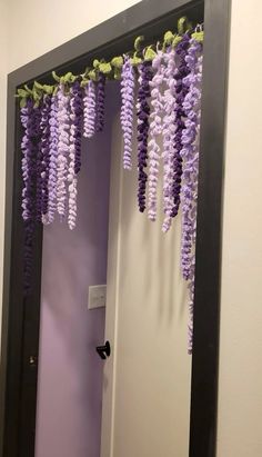 purple flowers are hanging from the ceiling in front of a mirror that is decorated with black trim