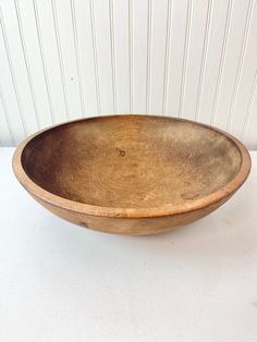 a wooden bowl sitting on top of a white table