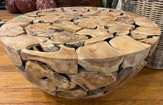 a table made out of wooden logs sitting on top of a hard wood floor next to wicker baskets