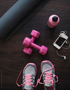 a pair of pink shoes and dumbs next to a cell phone