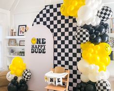 a room with black and white balloons, checkered wall and chair in the corner