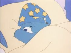 a blue teddy bear sleeping on top of a white bed covered in blankets and stars