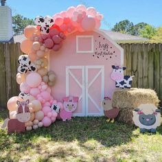 a pink barn decorated with balloons and farm animals