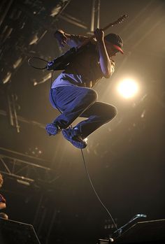 a man jumping in the air on top of a skateboard at a music concert