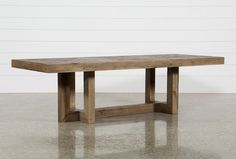 a large wooden table sitting on top of a cement floor next to a white wall