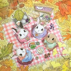 two rabbits are sitting at a picnic table surrounded by autumn leaves and other food items