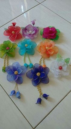 many different colored flowers on a white tile floor with gold chains and earring hooks