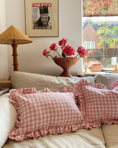 a couch with pillows and flowers on it in front of a window