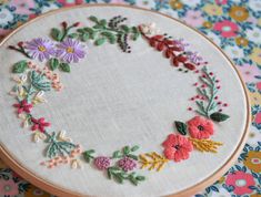 a close up of a embroidery on a table with flowers in the center and leaves around it