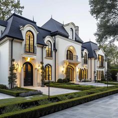 a large white house with lots of windows and bushes in front of the entrance to it