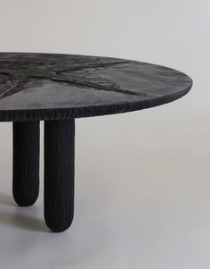 a round table with black wood legs and an abstract design on the top, against a white background