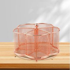 an orange wire basket sitting on top of a wooden table