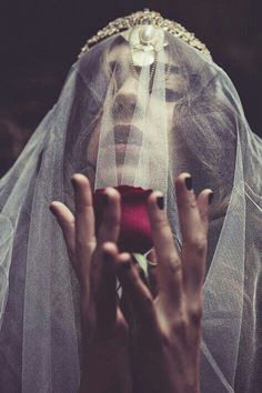 a woman wearing a veil and holding her hands up in front of her face