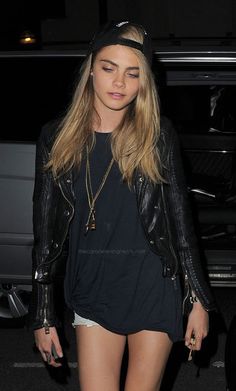 a woman in short shorts and a leather jacket is walking towards the camera with her hand on her hip