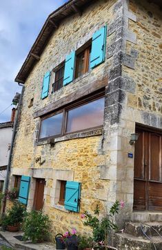 an old stone building with blue shutters and windows