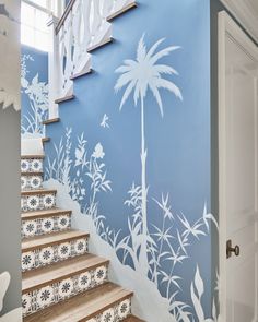 the stairs are painted with white flowers and palm tree stencils on blue walls