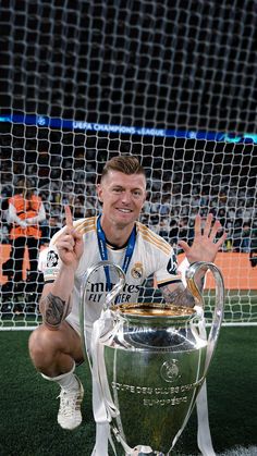 the soccer player poses with his trophy in front of the goalie's net
