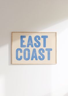 a sign that says east coast hanging on the wall in front of a white wall