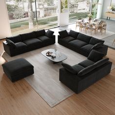 a modern living room with black couches and coffee table in front of large windows