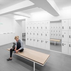 a person sitting on a bench in a room with many lockers and boxes behind them