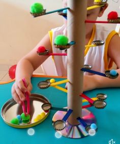 a young child is playing with some sort of crafting material on the table in front of her