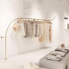 a clothing rack with clothes hanging from it's hooks in a white room next to a bench