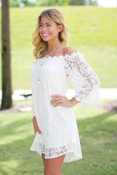 a beautiful woman posing for a photo in a white dress with lace detailing on the sleeves