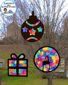 three colorful paper ornaments hanging from a tree