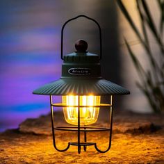 a green lantern sitting on top of a sandy ground