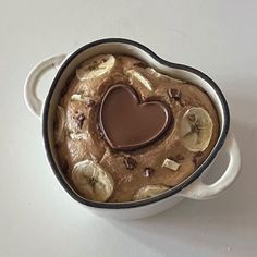 a heart - shaped chocolate pudding in a bowl with banana slices and other toppings