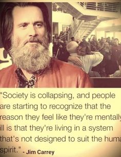 a man with a long beard standing in front of a poster that says society is collasing and people are starting to recognize