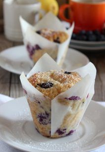 two blueberry muffins sitting on top of white plates with napkins around them