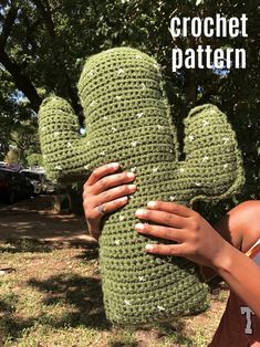 a woman is holding up a crocheted cactus