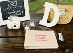 a wooden table topped with a sign and other personalized items next to a camera