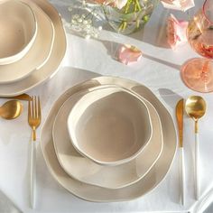 the table is set with plates, silverware and flowers in vases on it