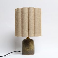 a lamp that is sitting on top of a table next to a white wall with a black cord