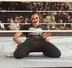 a man sitting on the ground in front of a wrestling ring with people watching him