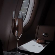 a glass of wine sitting on top of a table next to a window