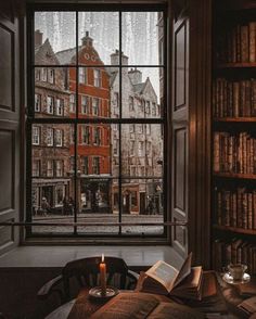 an open book sitting on top of a table next to a window filled with books