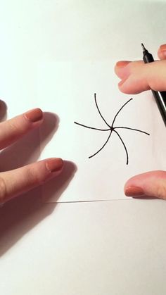 someone is drawing a spider on paper with a marker and pen while another hand holds the pencil