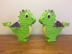 two green paper dragon sculptures sitting on top of a wooden table next to each other