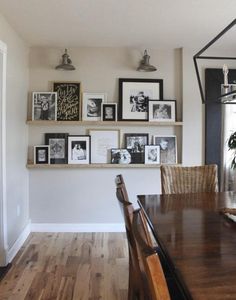 a dining room table with chairs and pictures on the wall