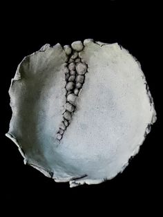 a white bowl with beads in it on a black surface