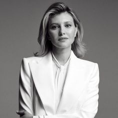 a black and white photo of a woman in a suit with her arms folded out