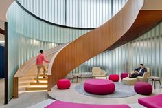 two people are sitting in chairs near a spiral staircase that leads up to the second floor