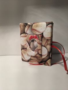 a small bag with baseballs on it and a red ribbon tied around the front