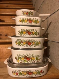 four white casserole dishes stacked on top of each other in front of stairs