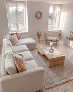 a living room filled with white furniture and lots of pillows on top of the couches