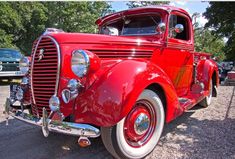 an old red car is parked on the gravel